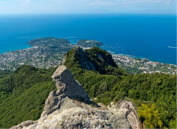 Vista panoramica dall'alto di un'isola con mare, montagne e vegetazione rigogliosa.