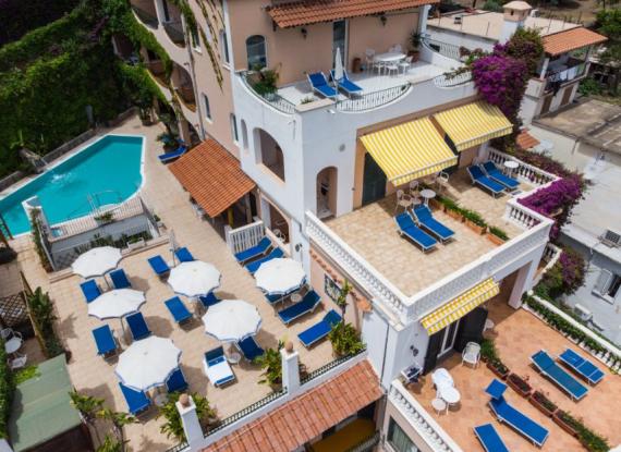 Terrazze con lettini, ombrelloni e piscina in un hotel mediterraneo.