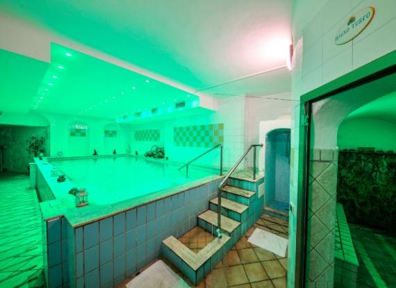 Piscina interna con illuminazione verde e ingresso al bagno turco.