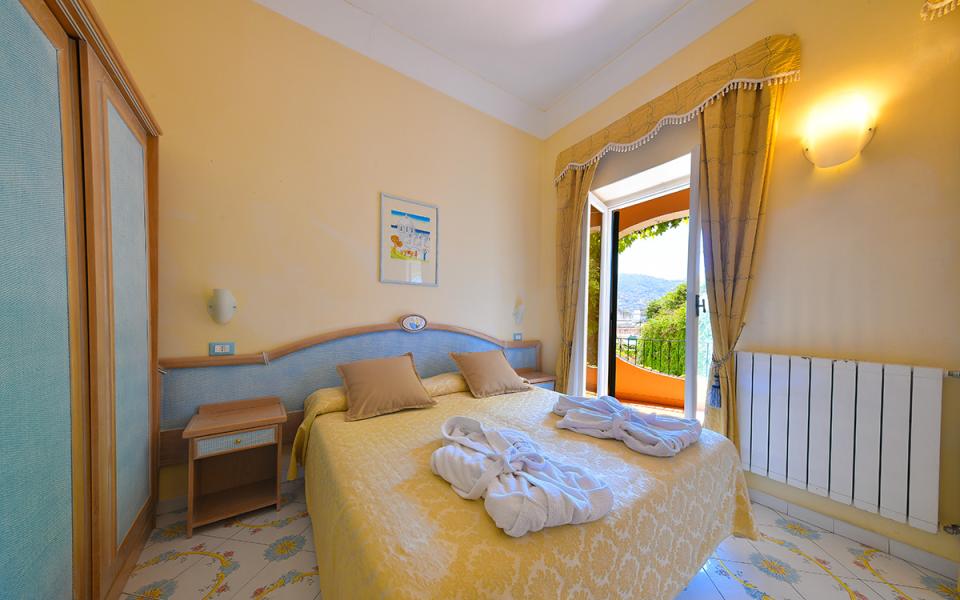 Camera luminosa con letto matrimoniale, vista esterna e arredi eleganti.