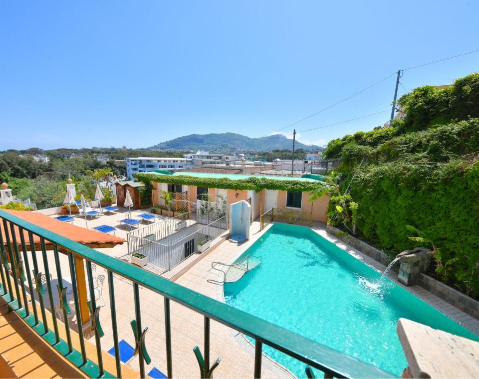 Piscina all'aperto con vista montagna, lettini e ombrelloni su terrazza soleggiata.