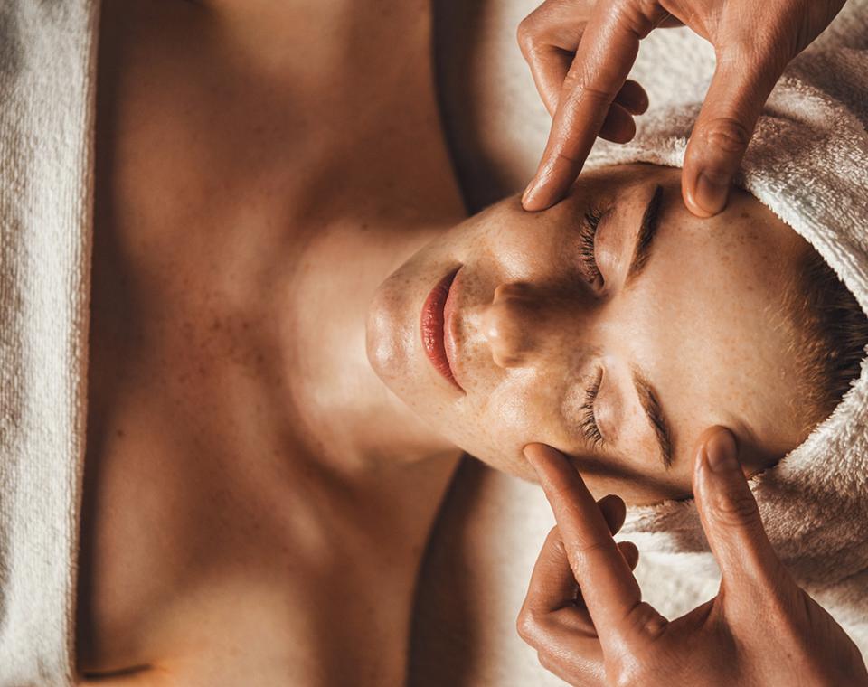 Massaggio rilassante al viso, mani esperte e atmosfera serena, pelle luminosa.