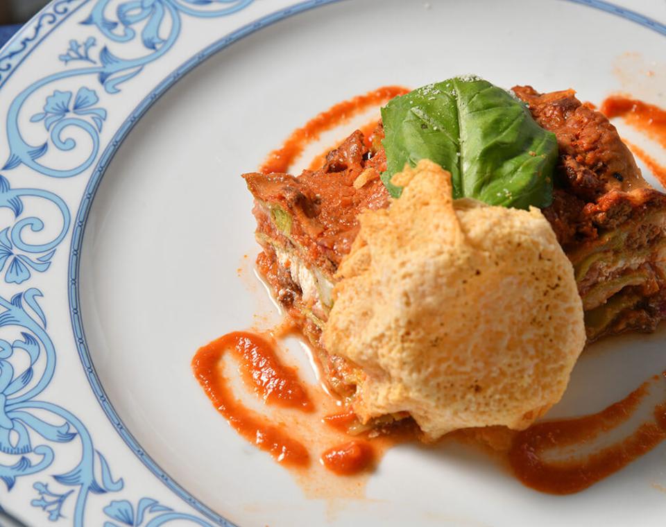 Lasagna cremosa con salsa rossa, foglia di basilico e croccante cialda di formaggio.