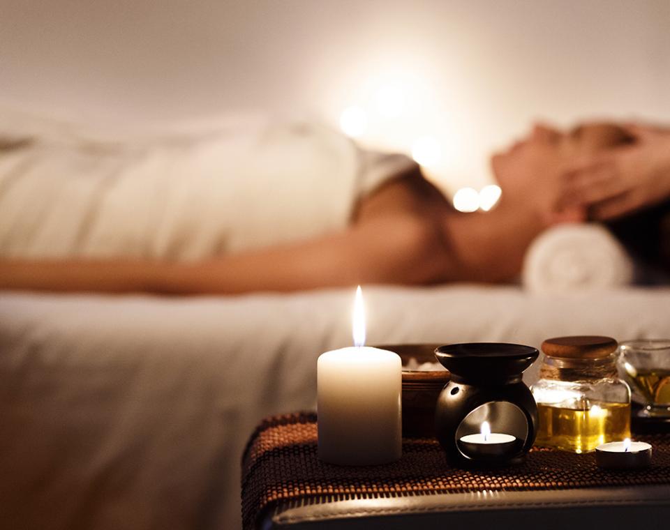 Atmosfera rilassante con candele, oli aromatici e massaggio rigenerante in un ambiente tranquillo.